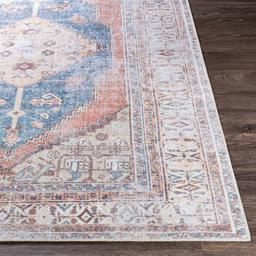 Close-up of the Lake Area Rug showing its bohemian-inspired pattern in navy, coral, tan, and light gray on a dark wood floor. Front