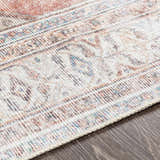 Close-up of the cotton Lake Area Rug. Features a traditional design in brown, coral, and light gray tones. Texture