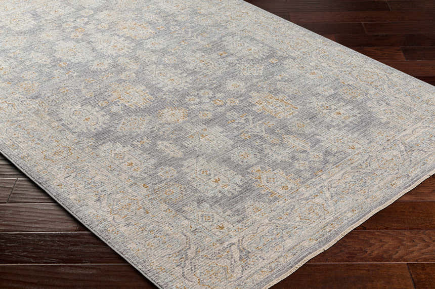 Close-up of Coby Brown Avant Garde rug showing traditional pattern in gray, beige, and gold on dark wood floors. Corner