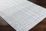 Close up of the Lubna Light Slate Area Rug showing the woven texture and slate, black, and charcoal colors. Corner