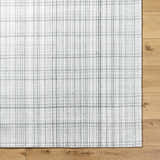 Close-up of the Lubna Light Slate Area Rug showing its woven texture and black, charcoal, and light slate plaid pattern. Corner