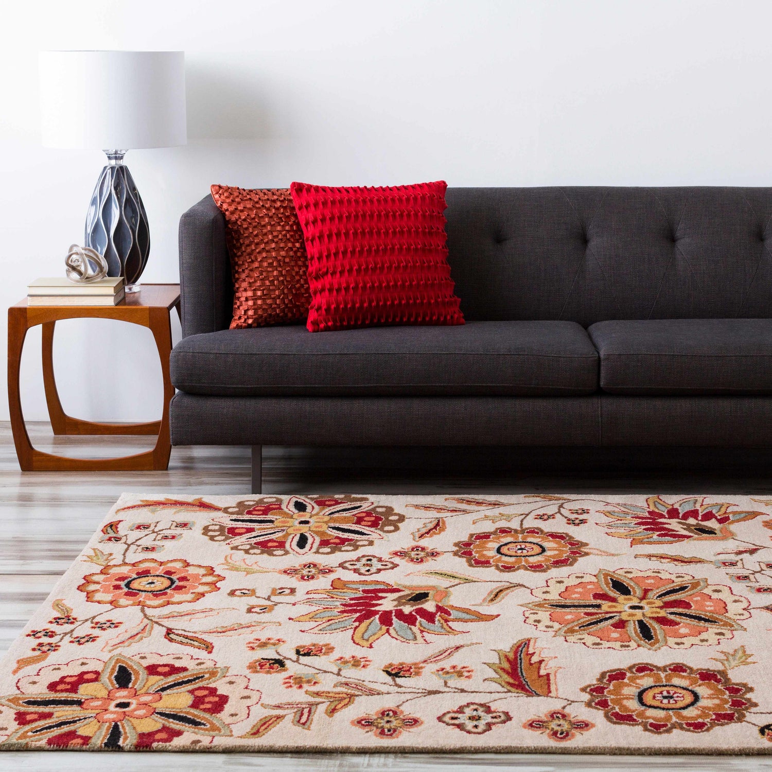 Living room scene with a Longford Beige Floral rug, gray sofa, wood side table, and bright red pillows. Roomscene-Rectangle
