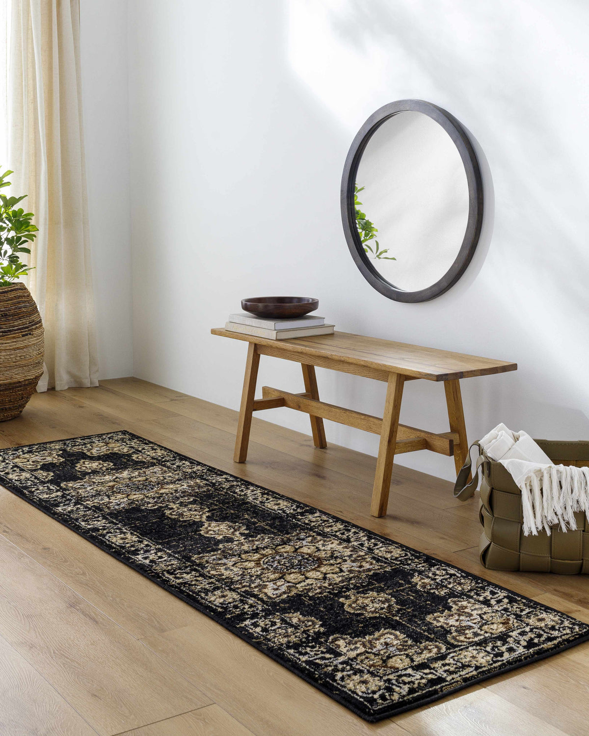 Entryway with a Lostwithiel Black Medallion Rug, wood floors, bench, mirror, and woven basket. Bohemian style. Roomscene-Runner
