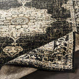 Close-up of the Lostwithiel Black Medallion Rug. Features a distressed black and beige traditional pattern. Fold