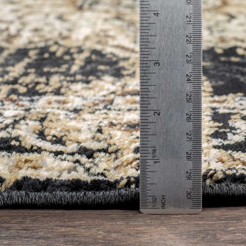 Close up of Lostwithiel Black Medallion Rug showing pile height with a ruler. Colors include black, beige, and tan. Pile