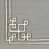 Close up of the Lott Area Rug. Gray wool rug with an ink blue and light gray geometric border pattern. Swatch
