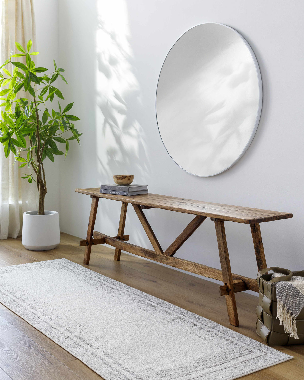 Entryway with Lovern Area Rug in charcoal, gray, and ivory. Farmhouse bench, round mirror, and potted plant create a bright, transitional space. Roomscene-Runner