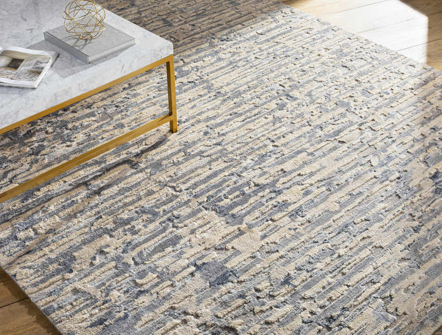 Close-up of the Lowdham Premium Rug. Contemporary design in cream, light beige, medium gray, and taupe. Hand-knotted viscose texture. Styleshot