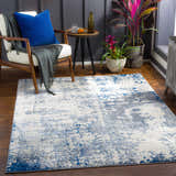 Living room scene with a Lubao Area Rug in blue, charcoal, cream, and light gray under a modern chair. Roomscene-Rectangle