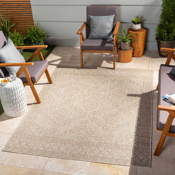 Stylish patio scene with the Lucea Indoor Outdoor Rug in cream and brown, surrounded by wood furniture and plants. Roomscene-Rectangle