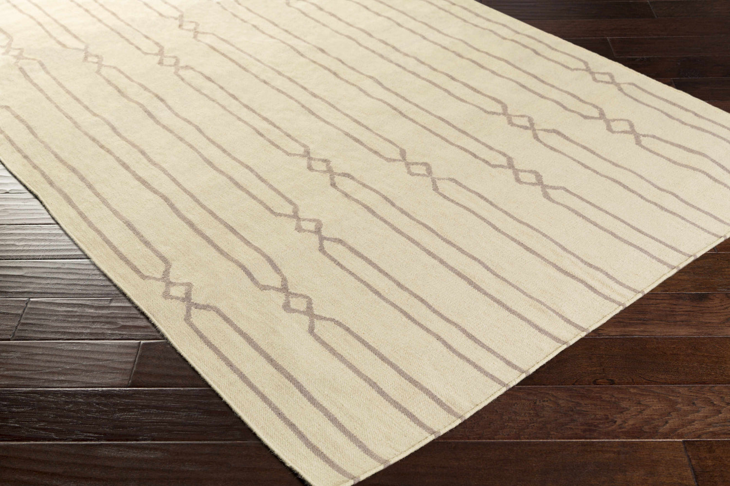 Close-up of the hand woven Luck Area Rug. Gray and wheat wool rug with farmhouse style linear diamond pattern. Corner