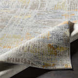 Close-up of the Ludington Area Rug showing its textured, distressed design in ivory, gray, yellow, and brown tones. Fold