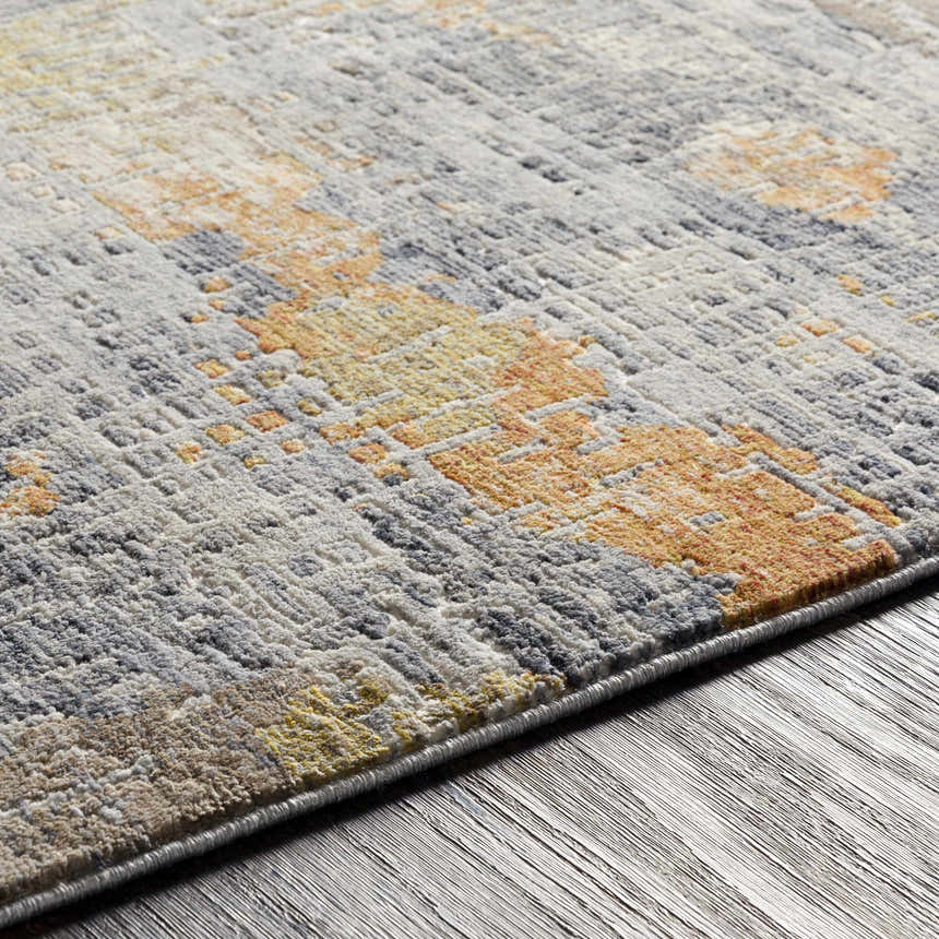Close-up of the Ludington Area Rug showing its gray, ivory, and orange vintage-style pattern and textured machine-woven construction. Texture