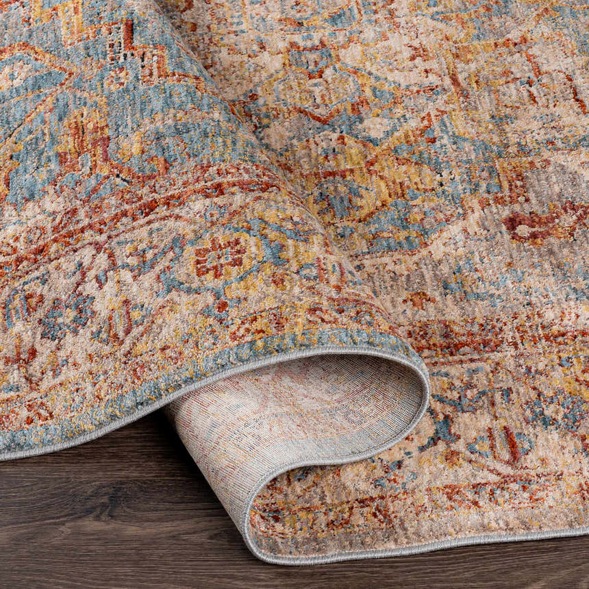Close up of the rolled edge of the Lumpkin Area Rug showing its brick red, teal, and beige oriental pattern. Fold