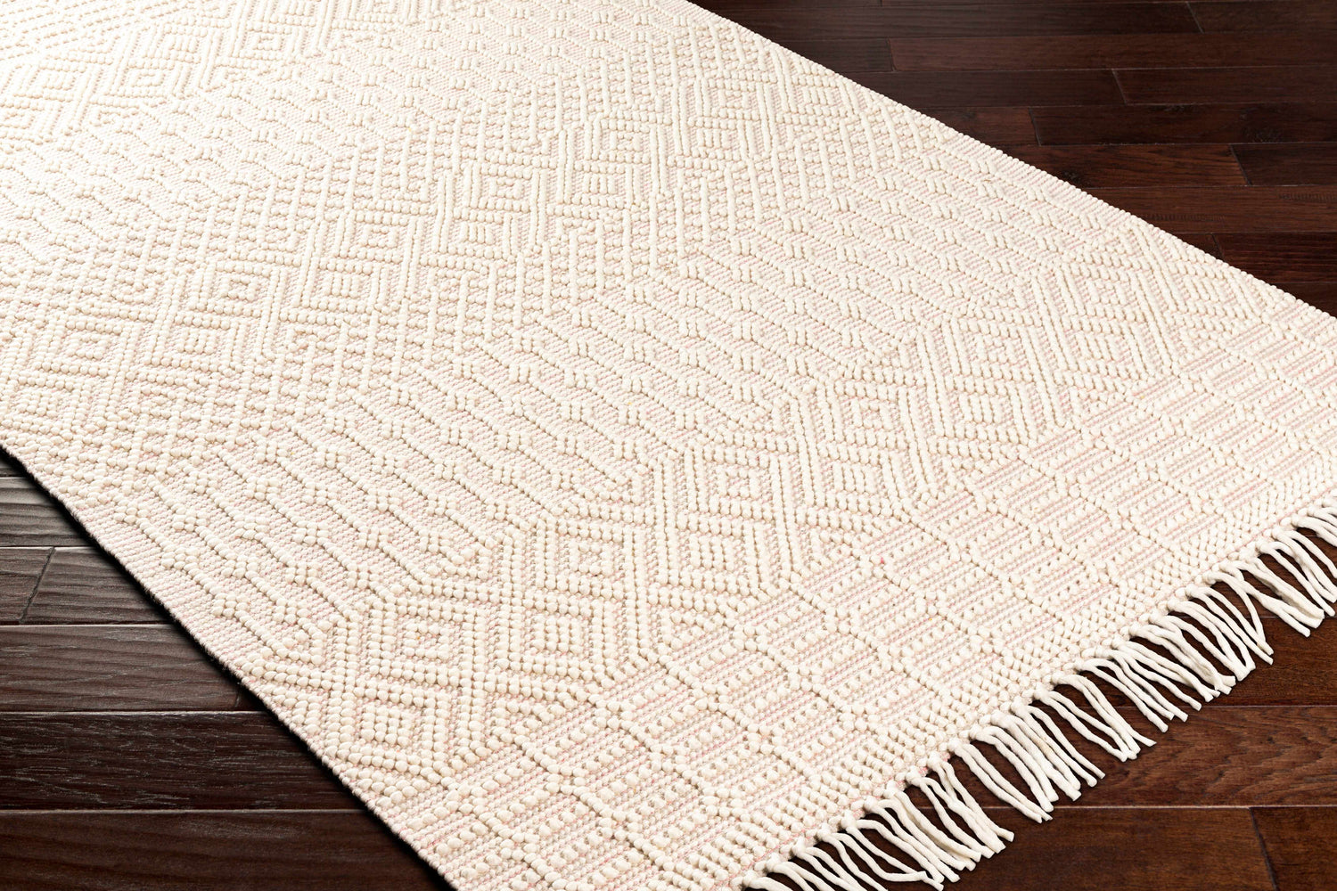Close up of the Luyu Area Rug. Hand woven rug with geometric pattern in cloud gray and light peach on dark wood floor. Corner