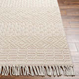 Close-up of the Luyu Area Rug showing its cloud gray, geometric, hand-woven design and fringe detail on hardwood floors. Front