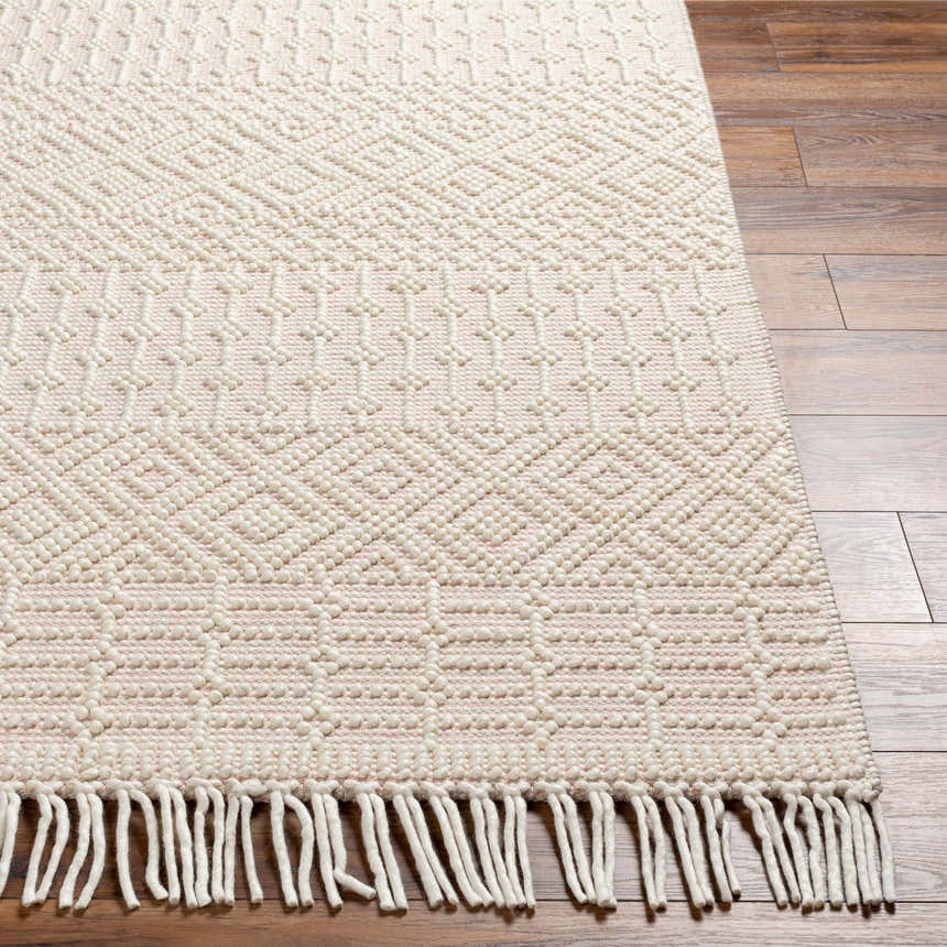 Close-up of the Luyu Area Rug showing its cloud gray, geometric, hand-woven design and fringe detail on hardwood floors. Front