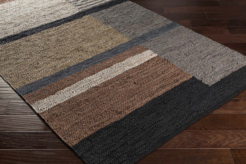 Close-up of the Lyndoch Leather Patchwork Rug. Features black, brown, and gray leather patches on a dark wood floor. Corner