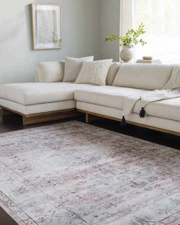 Living room scene with a Laran Taupe Distressed Washable Area Rug, light gray walls, and a cream-colored sectional sofa. Roomscene-Rectangle