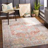 Cozy reading nook with a Rust Maayon Washable Rug, chair with patterned pillow, plants, and books. Roomscene-Rectangle