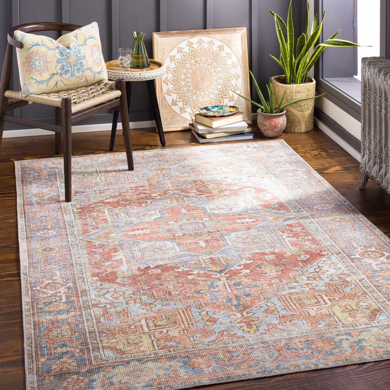 Cozy reading nook with a Rust Maayon Washable Rug, chair with patterned pillow, plants, and books. Roomscene-Rectangle
