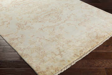 Close up of Macclenny Area Rug showing grass green and peach abstract pattern on hand knotted wool, with fringe detail. Corner