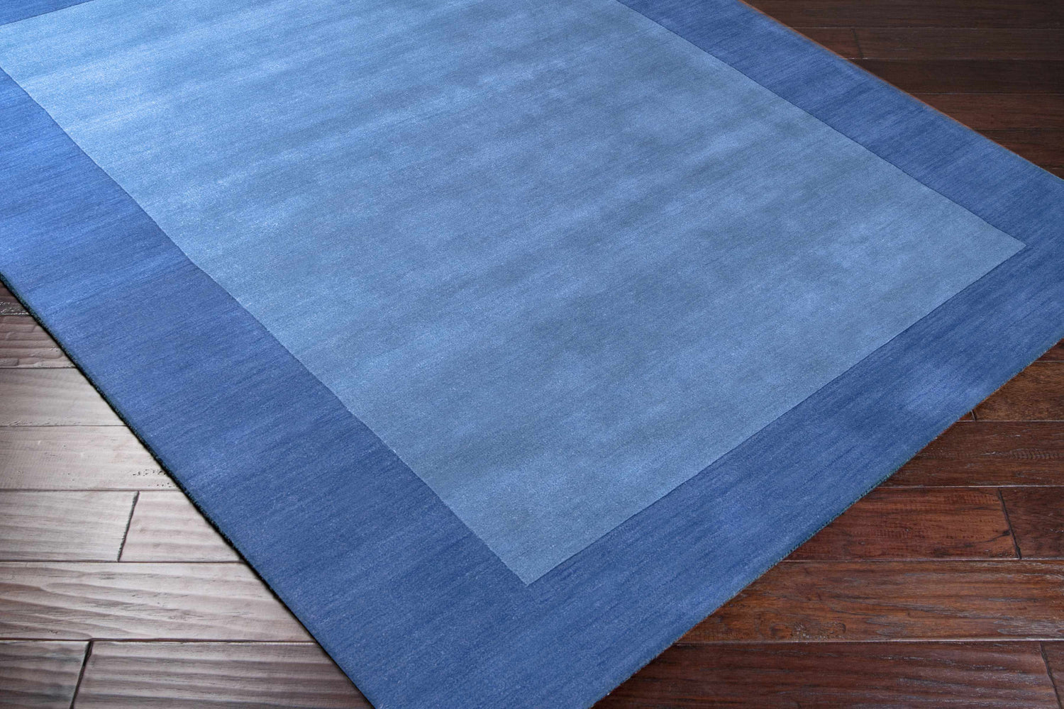 Close-up of the Macedon Blue Bordered Wool Rug showing its two-tone blue design and hand-loomed texture. Corner