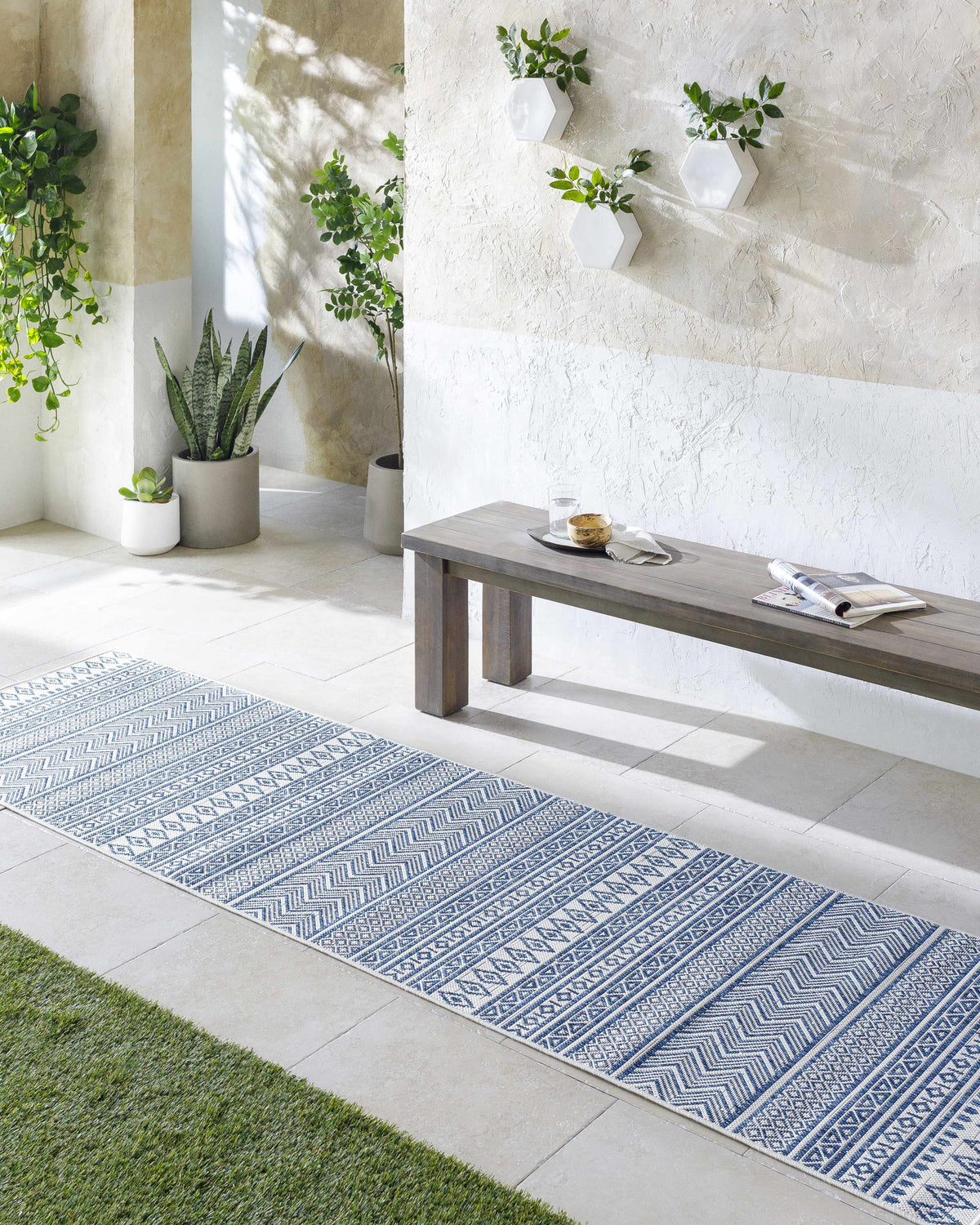 Bright entryway with a Madras Light Blue Green runner rug, wood bench, plants, and textured walls. Roomscene-Runner