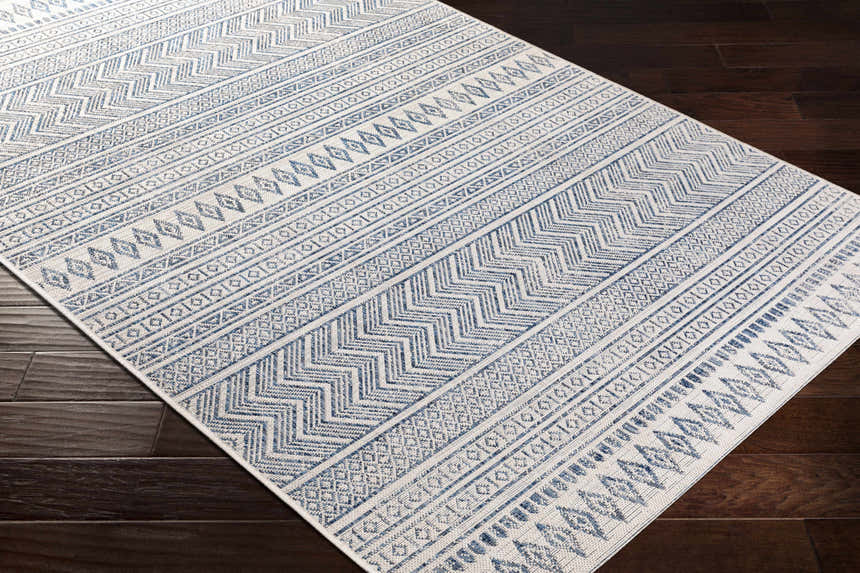 Close-up of Madras Light Blue Green All Over Performance Area Rug with geometric patterns on dark wood floor. Corner