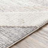 Close-up of the Magazine Geometric High/Low Pile Rug. Gray and tan rug with a geometric design and textured surface. Texture
