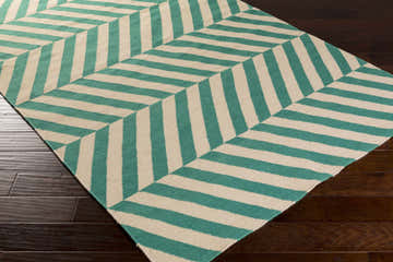 Close-up of Magdalena Area Carpet. Emerald and ivory stripes form a geometric chevron pattern. Hand-woven wool texture. Corner