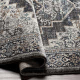 Close-up of the Manaring Luxe Thick Area Rug showing its traditional pattern and texture in shades of gray, blue, brown, and cream. Fold