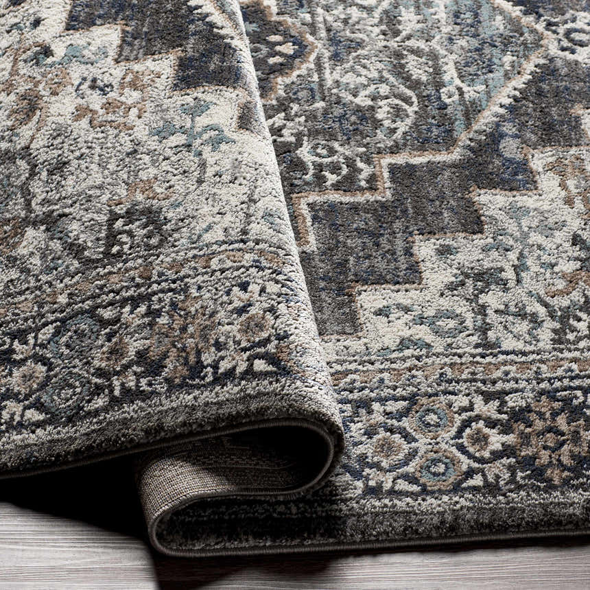Close-up of the Manaring Luxe Thick Area Rug showing its traditional pattern and texture in shades of gray, blue, brown, and cream. Fold