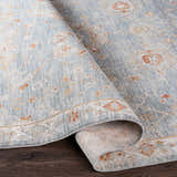 Close-up of the Mangham Thick Luxe Area Rug, showcasing its blue, beige, and rust traditional floral pattern. Fold