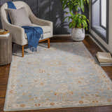 Living room scene with a blue and brick red Mangham Thick Luxe Area Rug, beige chair, and wood accents. Roomscene-Rectangle