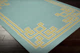 Close-up of the Manitou Area Rug, a contemporary hand-woven rug in aqua with a light olive geometric border. Corner