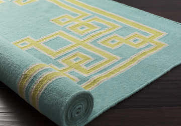 Close-up of a rolled Manitou Area Rug. Aqua wool rug with a geometric light olive and gray pattern. Hand woven texture. Styleshot