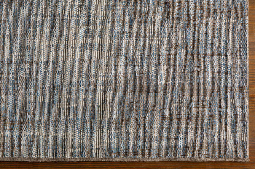 Close-up of the machine-woven Manzanita Area Rug. Features blue, cream, pale blue, and taupe threads. Corner