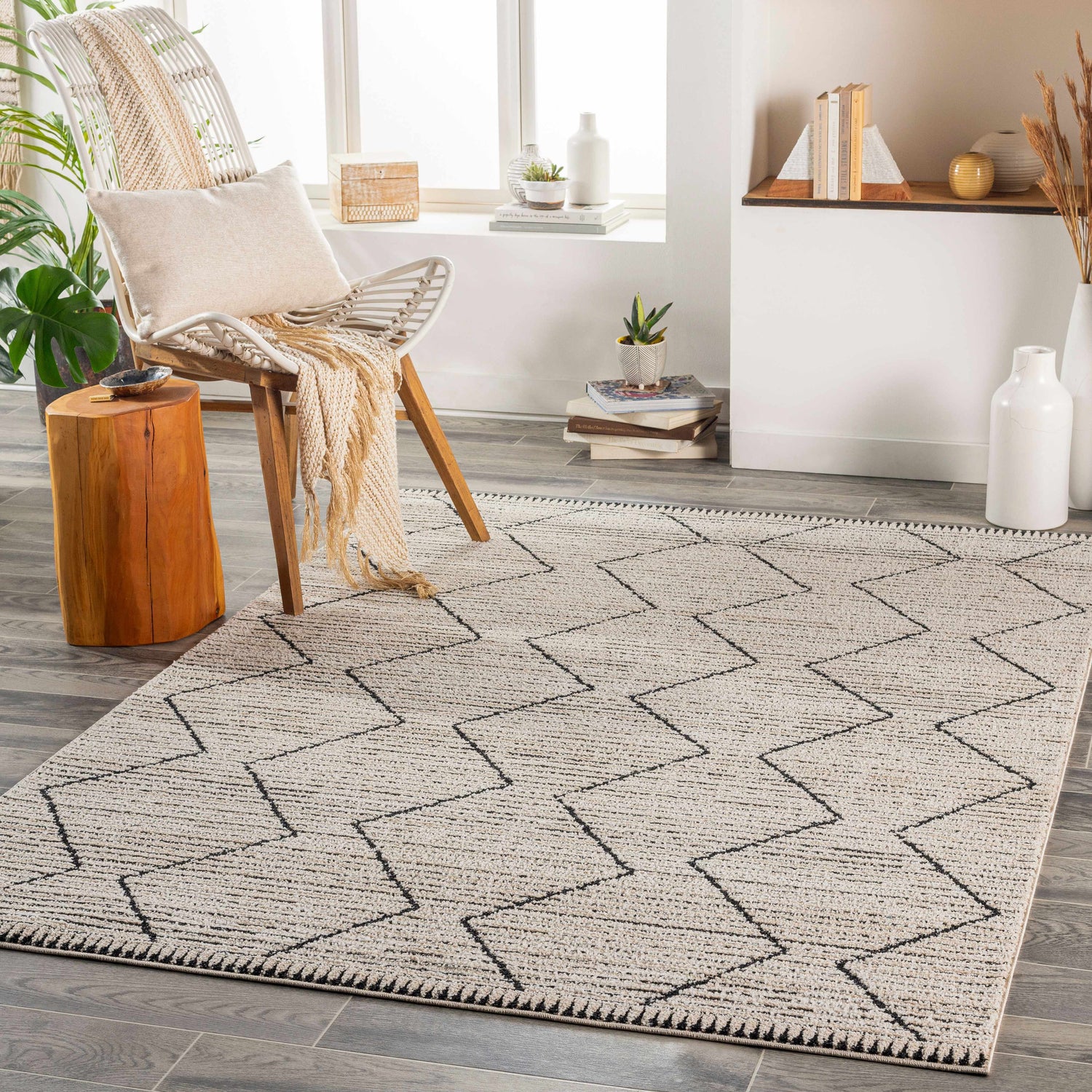 Living room scene with a geometric Maonon Area Rug in dark gray and lambswool, styled with a chair, wood stump table, and plants. Roomscene-Rectangle