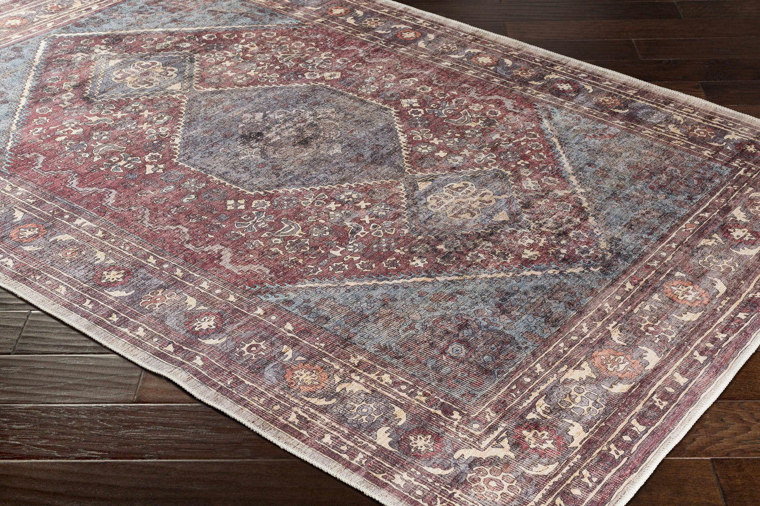 Close-up of the Maplesville Washable Area Rug showing its traditional beige, pink, and teal floral pattern and soft texture. Corner