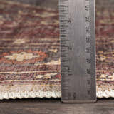 Close-up of Maplesville Washable Area Rug showing rug thickness with a ruler. Beige, pink, and plum traditional rug texture. Pile