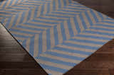 Close-up of the Mauckport Area Rug. Hand woven wool rug with charcoal and dark blue chevron pattern. Corner