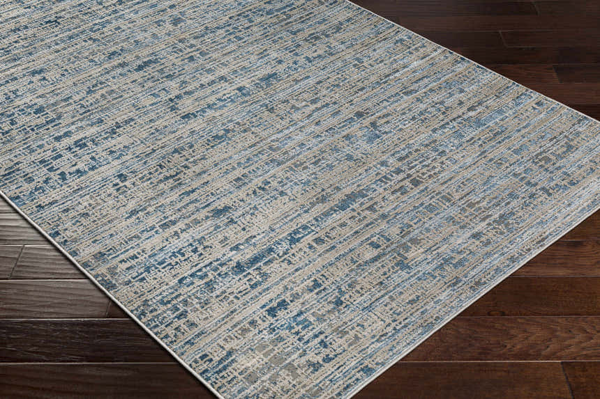 Close-up of the Maungatapere Area Rug, a contemporary rug in cream, gray, light beige, and teal on dark wood flooring. Corner