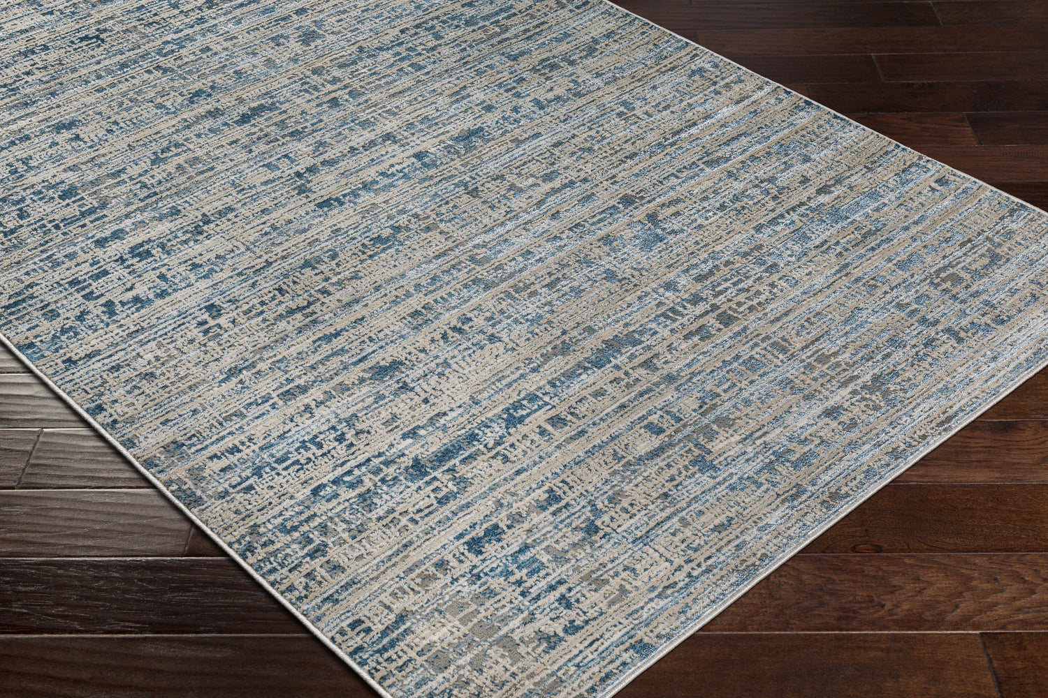 Close-up of the Maungatapere Area Rug, a contemporary rug in cream, gray, light beige, and teal on dark wood flooring. Corner