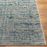 Close-up of the Maungatapere Area Rug, a contemporary rug in cream, gray, and teal on a wood floor. Front
