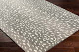 Close-up of Athena Gray Giraffe Print Wool Rug showing cream spots on light and medium gray wool, on dark wood floor. Corner