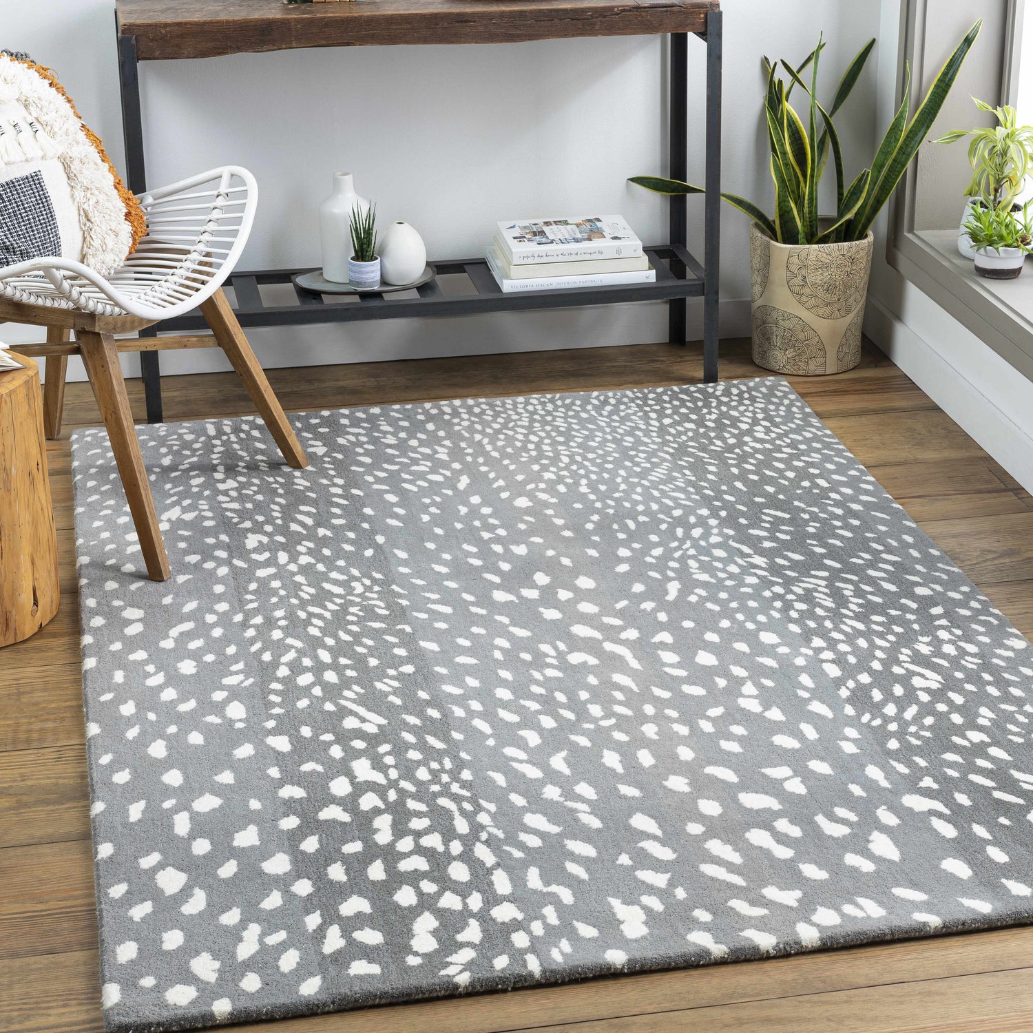 Living room scene with Athena Gray Giraffe Print Wool Rug, white chair, wood floors, console table, and plants. Roomscene-Rectangle
