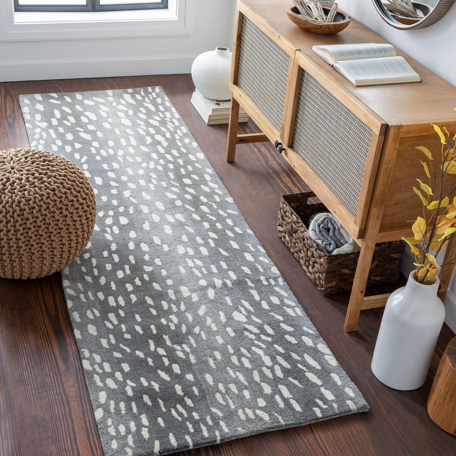 Entryway with wood floors and Athena Gray Giraffe Print Wool Rug. Console table, vase, and woven pouf complete the decor. Roomscene-Runner