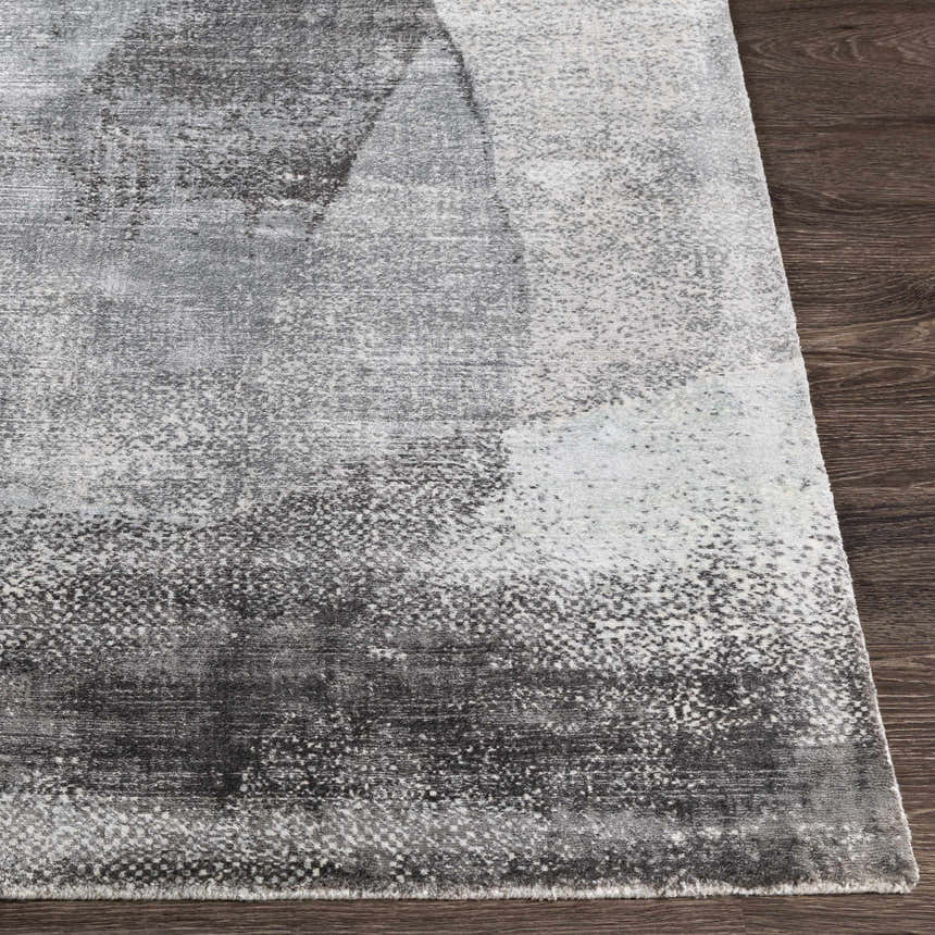 Close-up of the McDowall Viscose Area Rug showing its abstract pattern in black, charcoal, cream, and gray tones. Front