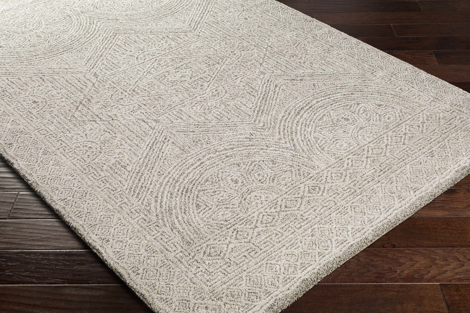 Close-up of the Middleville Luxe Rug. Contemporary style rug in charcoal, cream, and light beige with geometric patterns. Corner